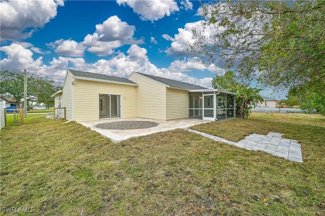 rear view of house with a sunroom, a lawn, and a patio area