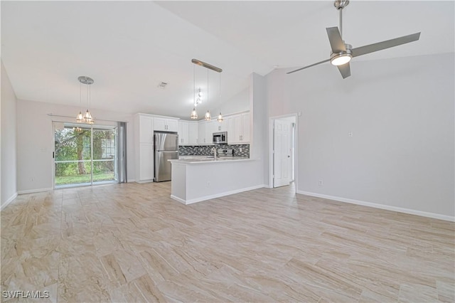 unfurnished living room with ceiling fan with notable chandelier and high vaulted ceiling