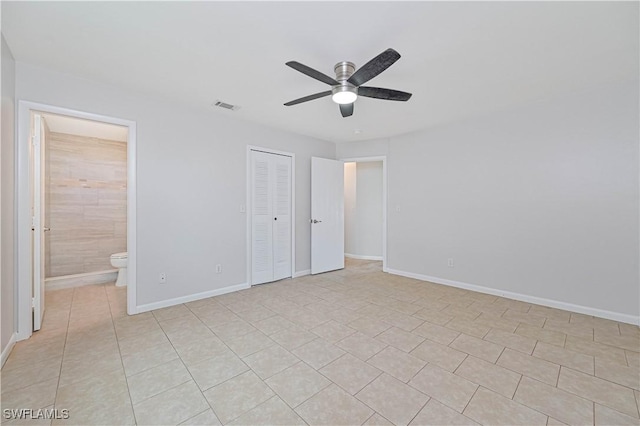 unfurnished bedroom with ceiling fan, connected bathroom, a closet, and light tile patterned floors