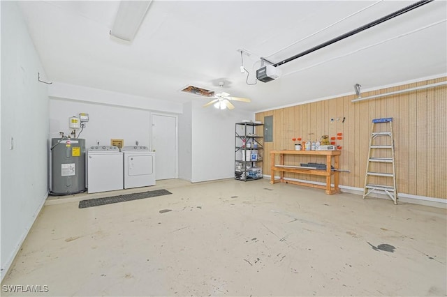 garage with washing machine and clothes dryer, a garage door opener, electric panel, electric water heater, and a workshop area