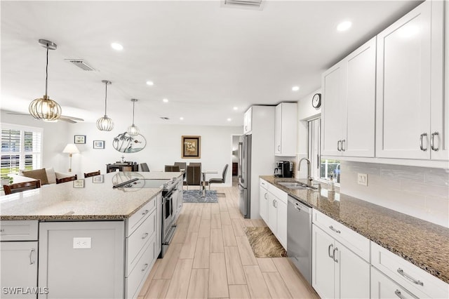 kitchen featuring white cabinetry, stainless steel appliances, sink, and a kitchen island