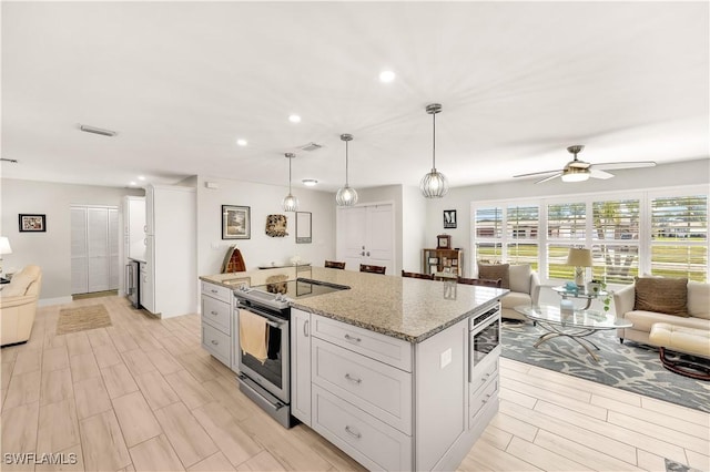 kitchen with pendant lighting, white cabinetry, a center island, stainless steel appliances, and light stone countertops