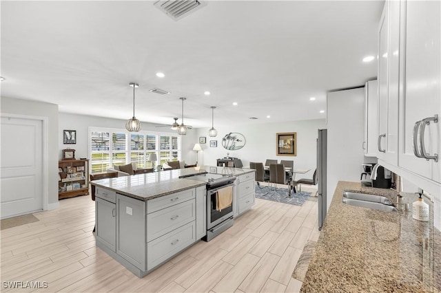 kitchen featuring sink, hanging light fixtures, a kitchen island, stainless steel appliances, and light stone countertops