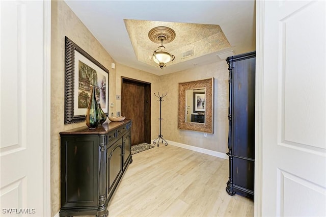 interior space with a raised ceiling and light hardwood / wood-style flooring