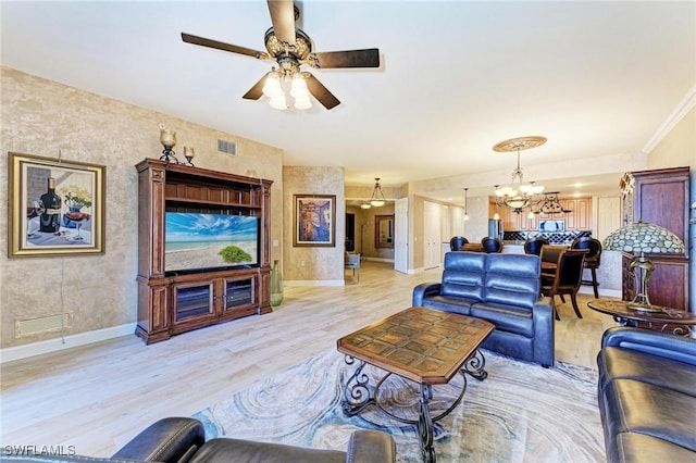 living room featuring crown molding, ceiling fan with notable chandelier, and light hardwood / wood-style floors