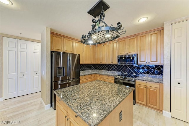 kitchen with a kitchen island, tasteful backsplash, dark stone counters, light hardwood / wood-style floors, and stainless steel appliances