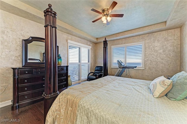 bedroom with dark wood-type flooring, access to outside, ceiling fan, and a tray ceiling