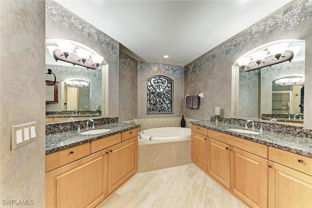 bathroom featuring vanity, tiled tub, and hardwood / wood-style floors