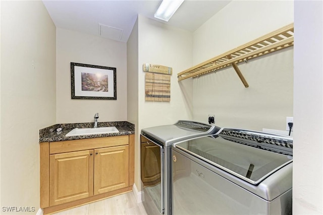 clothes washing area with cabinets, sink, and washing machine and dryer