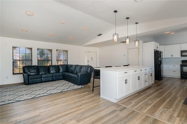 kitchen featuring hanging light fixtures, black appliances, white cabinets, a kitchen island, and vaulted ceiling