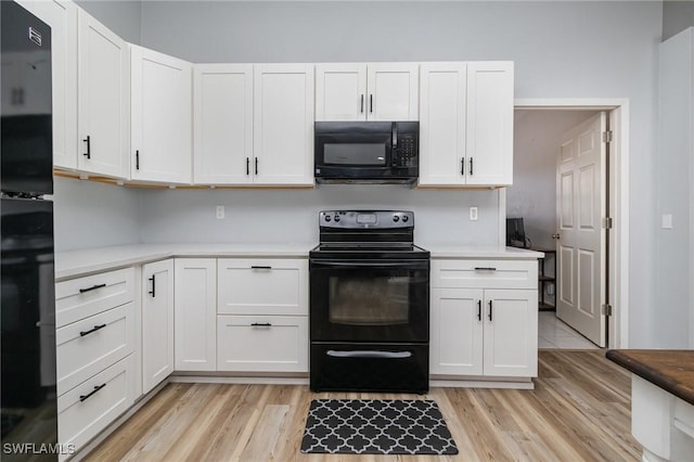 kitchen with light hardwood / wood-style flooring, white cabinets, and black appliances