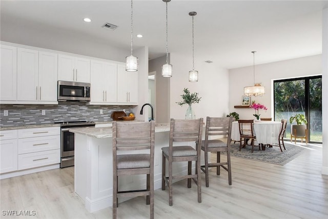 kitchen with white cabinetry, decorative light fixtures, tasteful backsplash, and appliances with stainless steel finishes