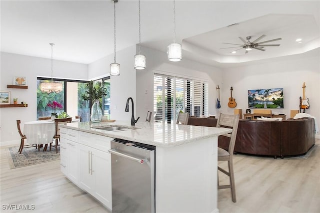 kitchen featuring dishwasher, white cabinetry, hanging light fixtures, a kitchen breakfast bar, and a center island with sink