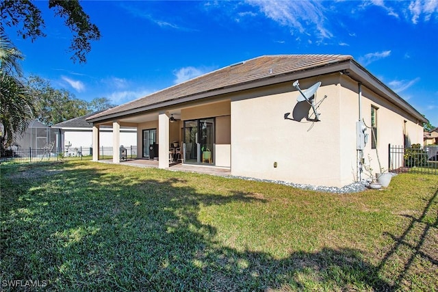 back of house with a patio and a lawn