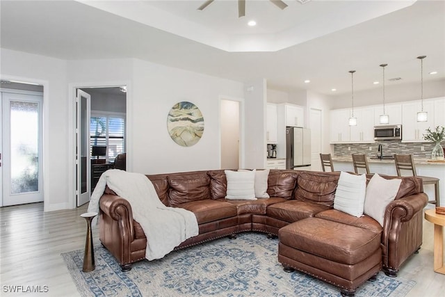 living room with ceiling fan, sink, and light wood-type flooring