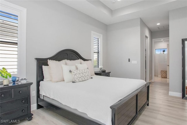 bedroom with connected bathroom and light hardwood / wood-style flooring