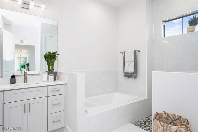 bathroom with vanity and tiled bath