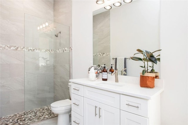 bathroom featuring vanity, toilet, and tiled shower