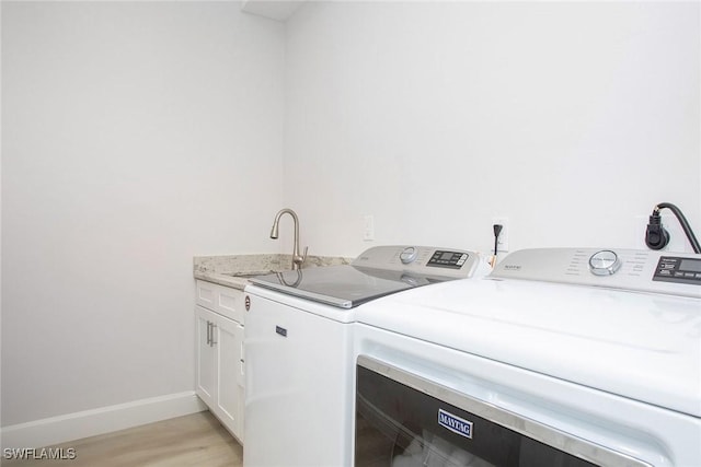 laundry area with cabinets, separate washer and dryer, sink, and light wood-type flooring