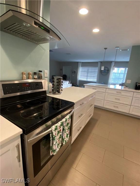 kitchen with hanging light fixtures, white cabinetry, island range hood, and stainless steel electric range