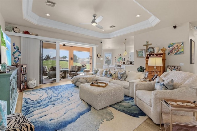 living room featuring crown molding, a tray ceiling, light hardwood / wood-style flooring, and ceiling fan