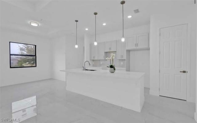 kitchen featuring white cabinetry, sink, decorative light fixtures, and a kitchen island