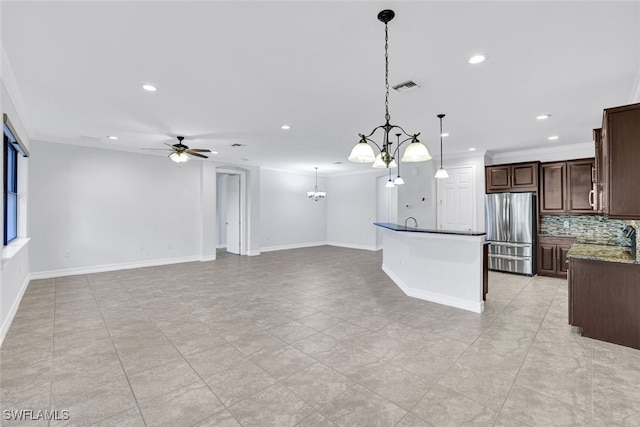kitchen with stainless steel refrigerator, tasteful backsplash, dark stone counters, hanging light fixtures, and dark brown cabinetry