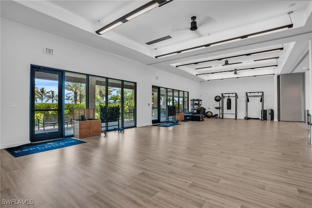 workout area with a towering ceiling, light hardwood / wood-style floors, and ceiling fan