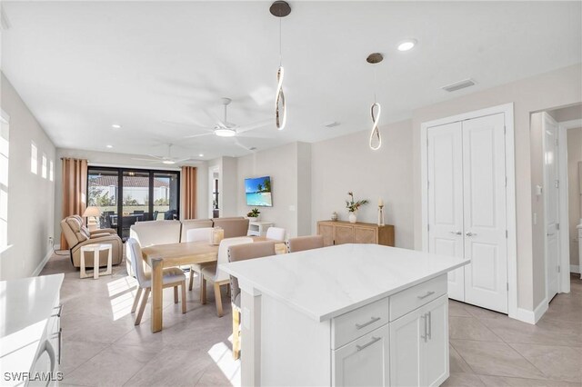 kitchen with a kitchen island, decorative light fixtures, white cabinetry, light tile patterned floors, and ceiling fan