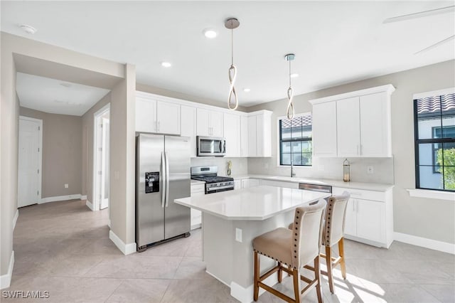 kitchen with white cabinetry, stainless steel appliances, a healthy amount of sunlight, and a kitchen island