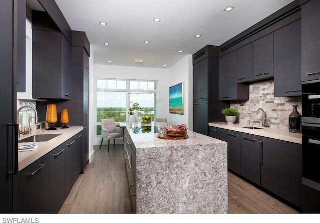 kitchen featuring tasteful backsplash, a kitchen island, sink, and oven