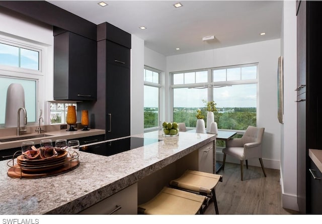 kitchen with black electric stovetop, hardwood / wood-style floors, sink, and a kitchen bar