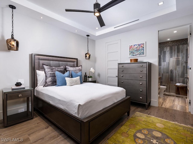 bedroom featuring dark hardwood / wood-style floors, connected bathroom, and a raised ceiling