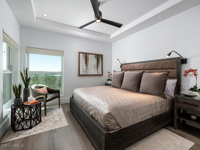 bedroom featuring ceiling fan, a raised ceiling, and hardwood / wood-style floors