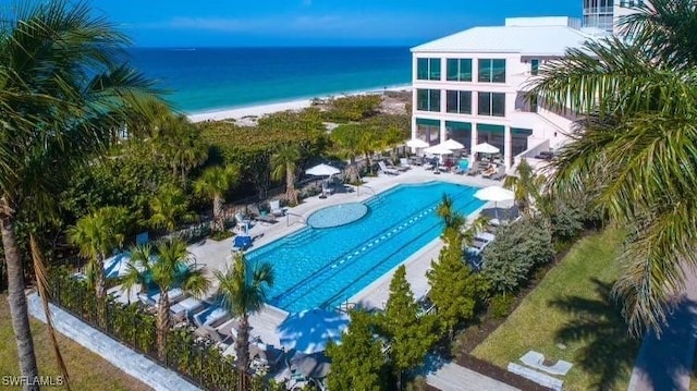 view of swimming pool with a patio area, a beach view, and a water view