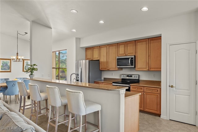 kitchen featuring pendant lighting, light tile patterned floors, stainless steel appliances, a notable chandelier, and a kitchen bar