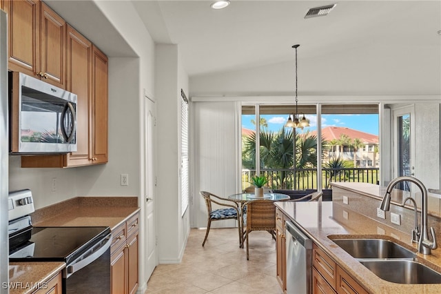 kitchen featuring appliances with stainless steel finishes, pendant lighting, lofted ceiling, sink, and light stone countertops