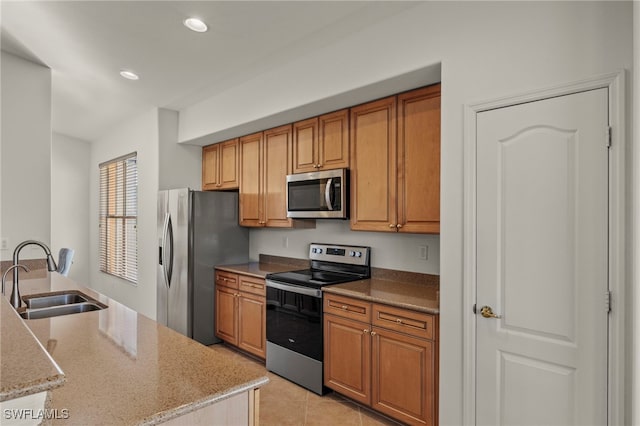 kitchen featuring light stone counters, sink, light tile patterned floors, and appliances with stainless steel finishes