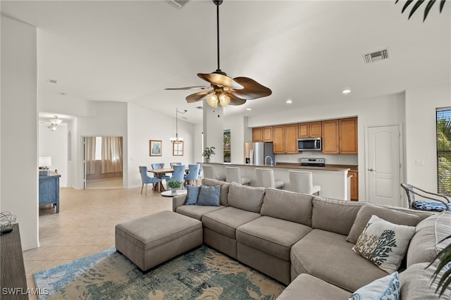 living room with ceiling fan with notable chandelier, light tile patterned floors, and lofted ceiling