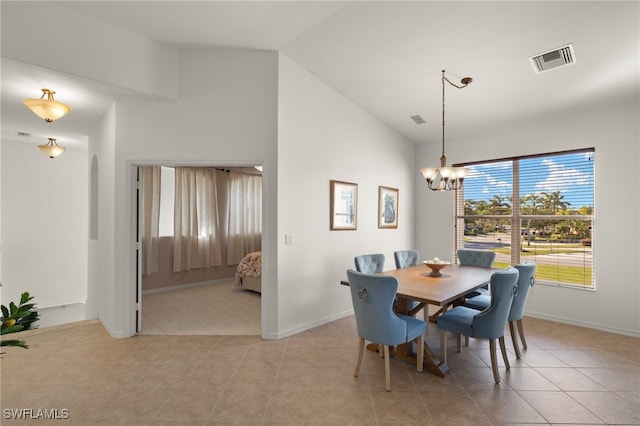 tiled dining space featuring an inviting chandelier and high vaulted ceiling