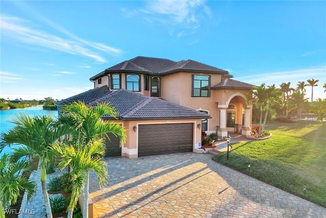 mediterranean / spanish home featuring a water view, a garage, and a front yard