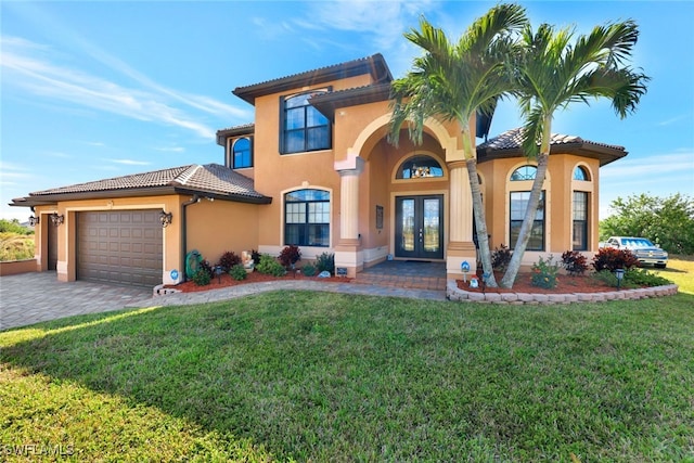 mediterranean / spanish house with a garage, a front yard, and french doors