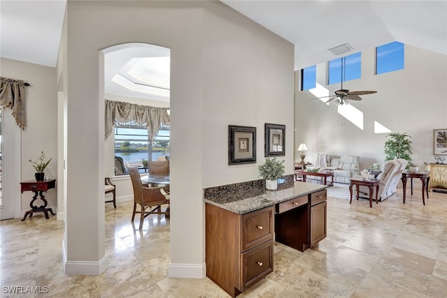 kitchen featuring light stone counters, high vaulted ceiling, and ceiling fan