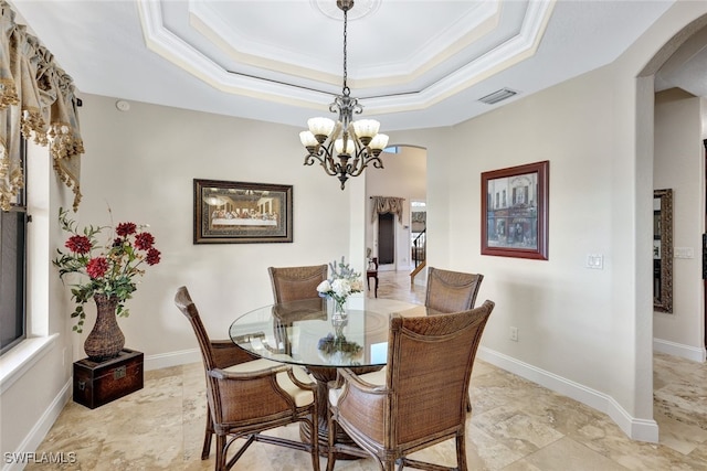 dining space with a tray ceiling, ornamental molding, and a chandelier