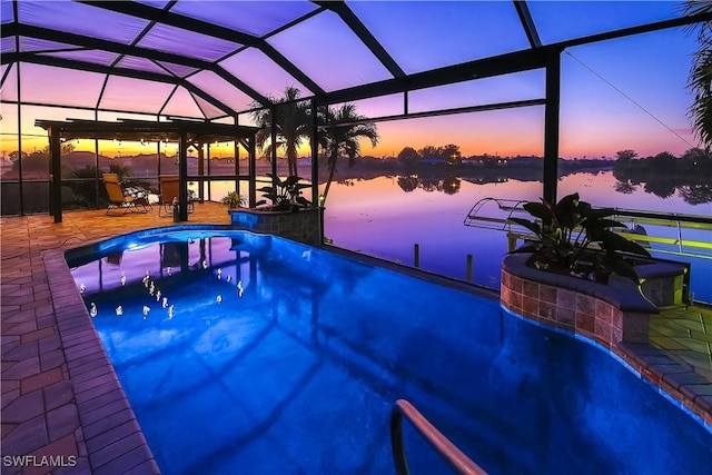 pool at dusk featuring a water view, a patio, and glass enclosure