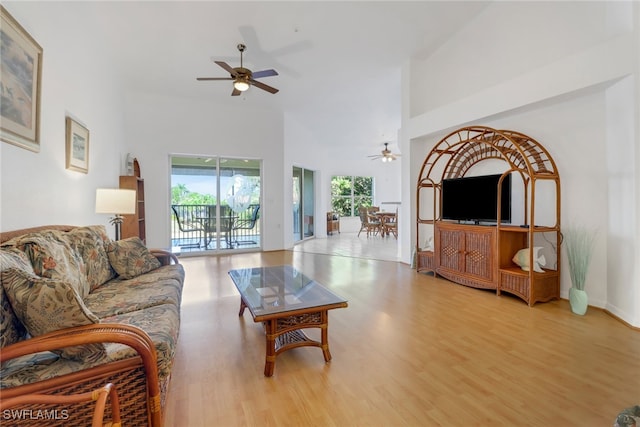 living room featuring ceiling fan, light hardwood / wood-style flooring, and a high ceiling