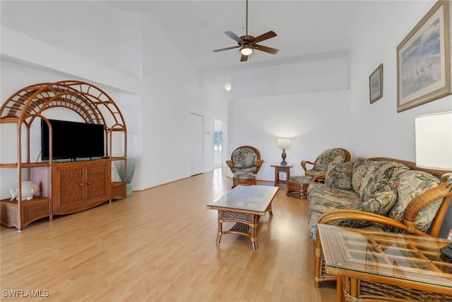 living room with light hardwood / wood-style flooring, ceiling fan, and a high ceiling