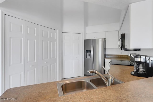 kitchen with sink, stainless steel appliances, white cabinets, and a high ceiling