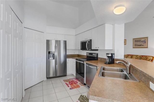 kitchen featuring stainless steel appliances, sink, light tile patterned floors, and white cabinets