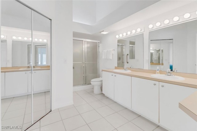 bathroom with an enclosed shower, vanity, tile patterned floors, and toilet